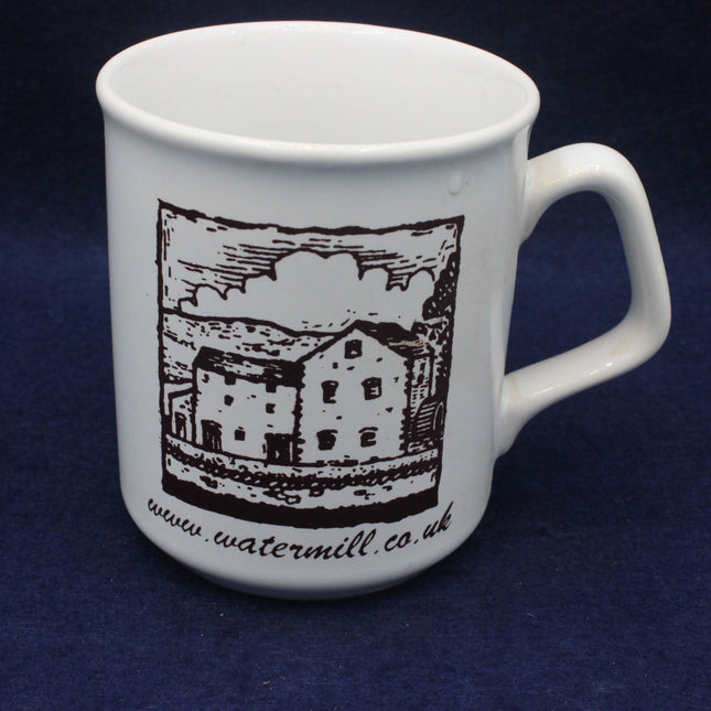 White mug with black illustration of a watermill and text on a dark blue background