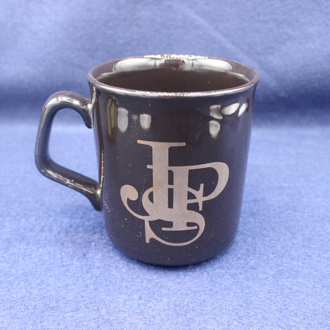 Black mug with JPS logo on a blue background