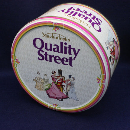 Round Quality Street tin on a dark background