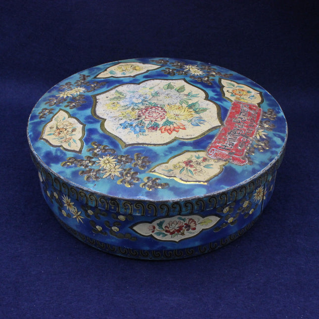 Decorative round biscuit tin with floral patterns on a blue background