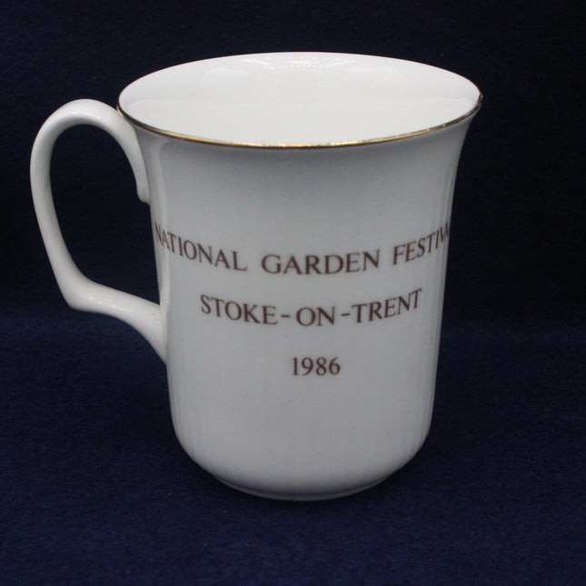 White mug with National Garden Festival text on a dark blue background
