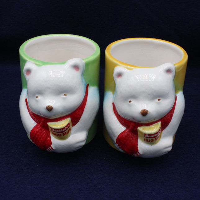 Two bear-shaped ceramic mugs with colorful rims on a dark background