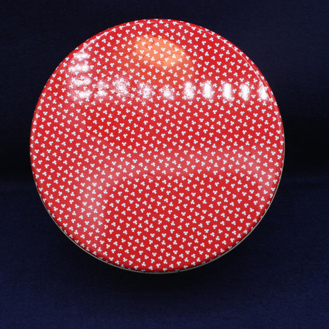 Red vintage tin with white floral pattern on a dark blue background