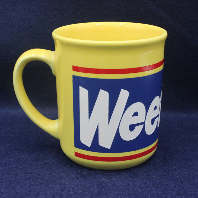 Yellow mug with a blue label featuring the word 'Weetabix' on a dark blue background