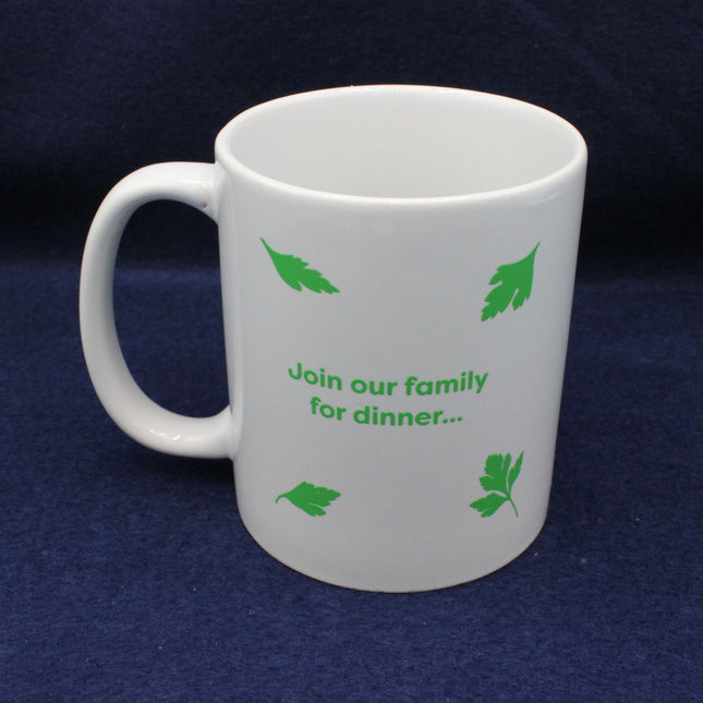 White mug with green text and leaf patterns on a dark blue background