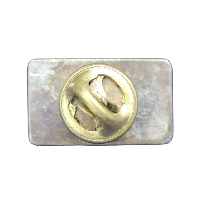 Metallic badge with a gold emblem on a white background