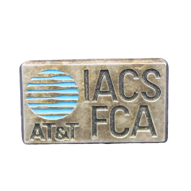 Metallic badge with 'IACS FCA' text on a blue fabric background