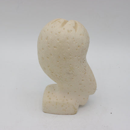 A small sculptural bust or decorative object with a perforated, porous texture, shown in a warm off-white or cream color against a plain light gray background.