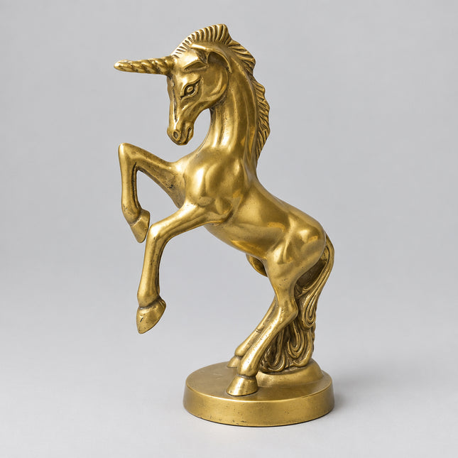 A metallic gold unicorn figurine standing on a round base, set against a bright green backdrop.