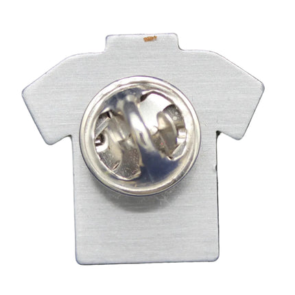 White shirt-shaped pin with a silver brooch on a blue fabric background