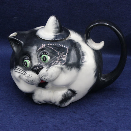 Cat-shaped teapot with black and white design on a blue background
