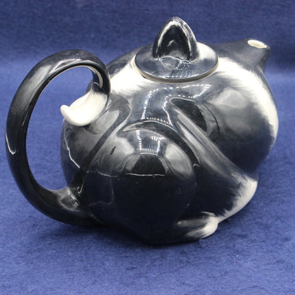 Black and white cat-shaped teapot on a blue background