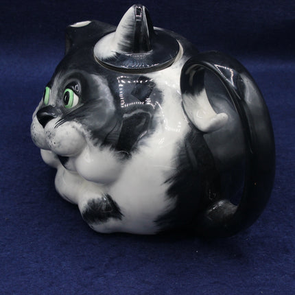 Cat-shaped teapot with black and white design on a blue background