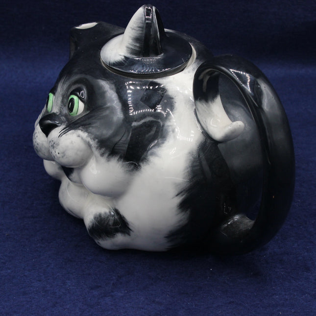 Cat-shaped teapot with black and white design on a blue background