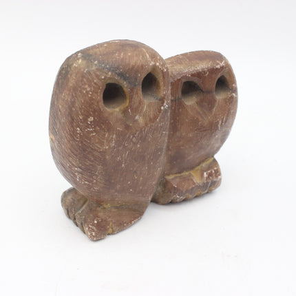 A small carved brown stone owl figurine with two eyes and a textured natural finish, photographed on a plain white background.