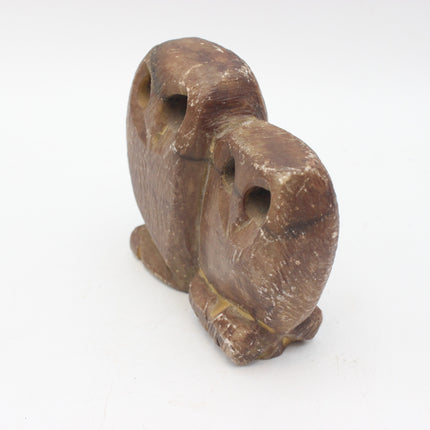 A small carved brown stone owl figurine with hollow eyes, photographed on a plain white background.