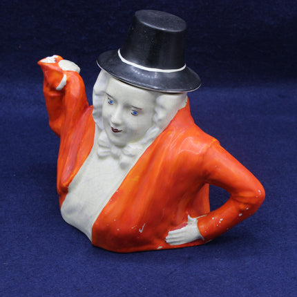 Ceramic bust of a person wearing an orange coat and black top hat on a blue background