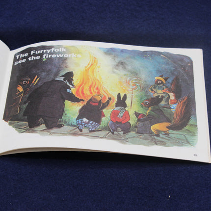 Illustrated book page showing characters watching fireworks with text 'The Furryfolk see the fireworks'.