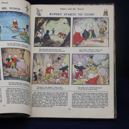 Open book with illustrations of Rupert the Bear and Mr. Punch, on a dark background.