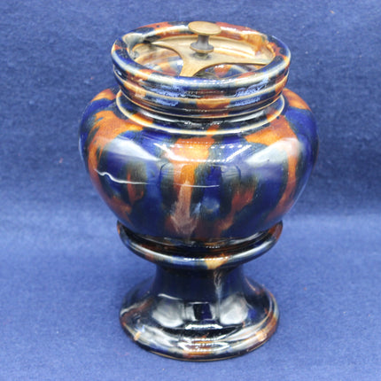 Decorative ceramic container with a blue and orange glaze on a blue background