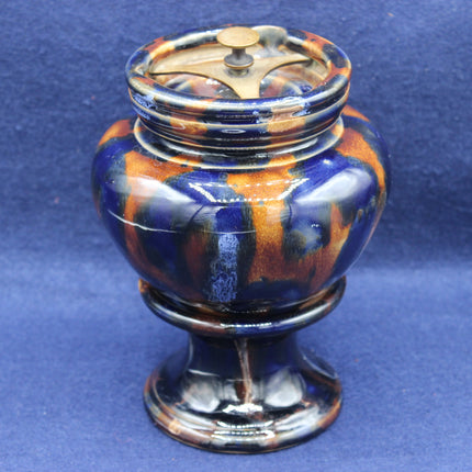 Decorative ceramic urn with blue and orange glaze on a blue background