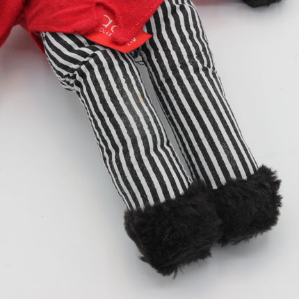 Close-up of a Golly doll's legs wearing black and white vertically striped pants with fluffy black boot covers, and a red top visible at the top edge.