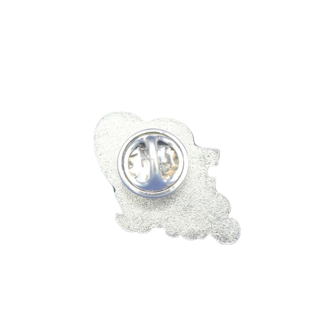 A silver metal lapel pin shown from the back, featuring a textured outline of a cartoon character and a circular pin clasp, placed on a textured blue background.