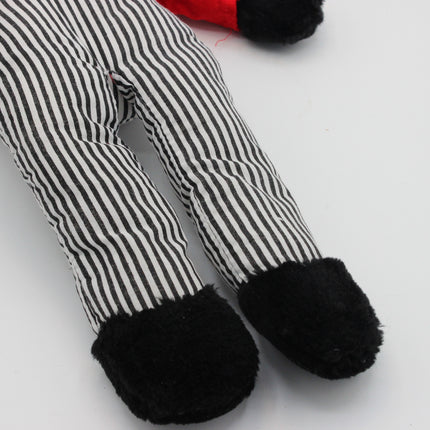 Close-up of a striped fabric Golly doll leg with black-and-white vertical stripes and black fuzzy feet, on a plain white background.
