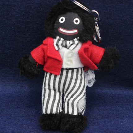 Stuffed toy Golly figure with a red coat, black and white striped pants, and a smile on a blue background
