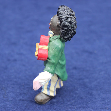 Figurine of a person in a green coat with a red bag on a blue background