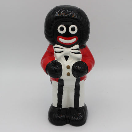A glossy black and white Golly figurine of a character with a red jacket, white shirt, and black pants, standing against a light gray background.