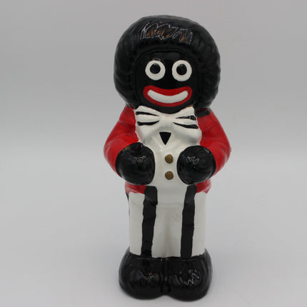 A glossy ceramic figurine of a character with a black afro hairstyle, white face, red lips, a red jacket, and a white tuxedo with black stripes and gold buttons, standing against a neutral gray background.