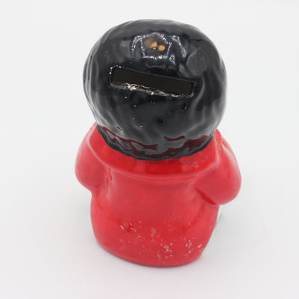 A novelty ceramic Golly piggy bank shaped like a person with a glossy black head and a red body, photographed against a plain white background.