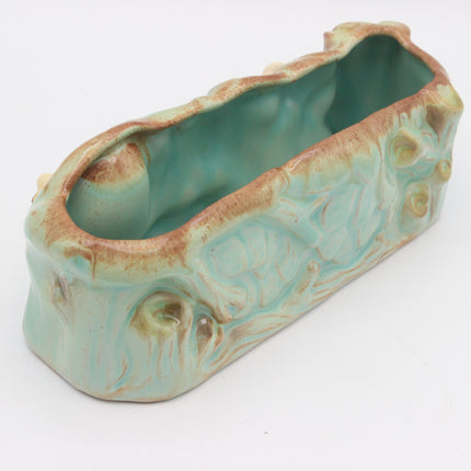 A rustic, elongated ceramic planter with a textured, bark-like exterior and a glossy turquoise-green glazed interior, shown on a plain white background.
