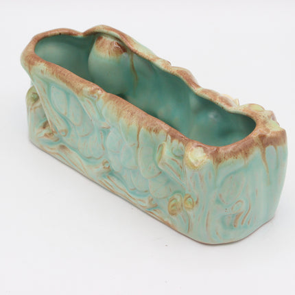 A vintage ceramic planter with a textured, organic shape and a glossy light green glaze with brown drips, shown on a white background.