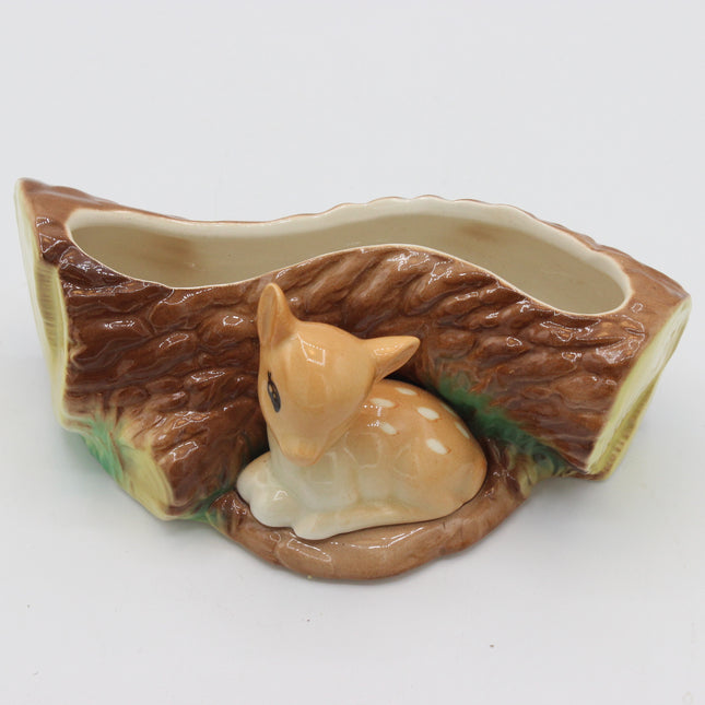 A ceramic woodland-themed planter shaped like a log slice with a small deer figurine nestled inside, on a plain white background.
