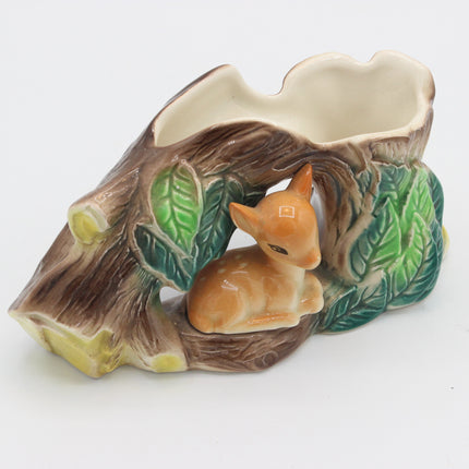 A ceramic woodland-themed planter shaped like a tree trunk with a small glazed fawn figurine nestled inside, set against a plain white background.