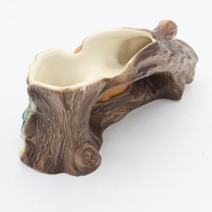 A ceramic planter shaped like a tree trunk, featuring a textured brown bark exterior and a smooth cream-colored interior, shown on a plain white background.