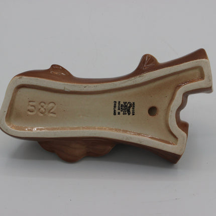 A ceramic dog toy shaped like a pistol, showing the interior base with the number 582 and a maker's mark.