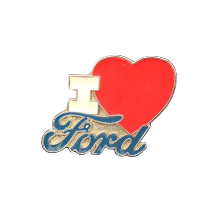 An enamel lapel pin featuring a red heart, a gold block 'I', and the word 'Ford' in blue cursive script, displayed on a textured dark blue background.