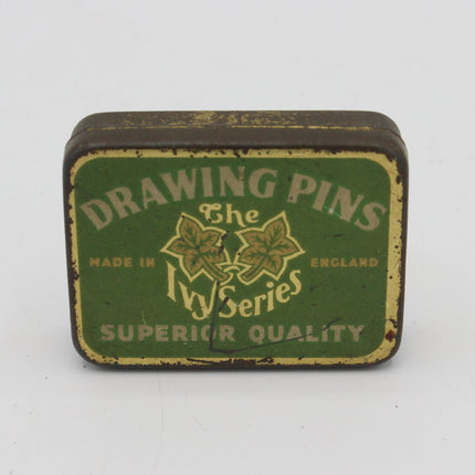 A vintage rectangular metal tin of 'The Ivy Series Drawing Pins' on a plain white background. The tin features a distressed green label with cream-colored text and ivy graphics, showing signs of age and wear.