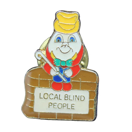 Pin with a cartoon character and 'Local Blind People' text on a blue background