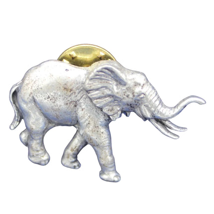 Silver elephant figurine with a gold coin on its back against a blue background