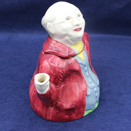 Vintage ceramic figure of a woman in a red coat holding a white object on a blue background