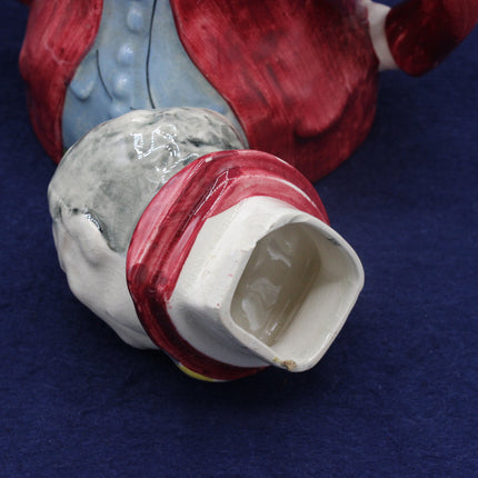 Close-up of a ceramic or porcelain figurine with red, white, and blue colors on a dark blue background.