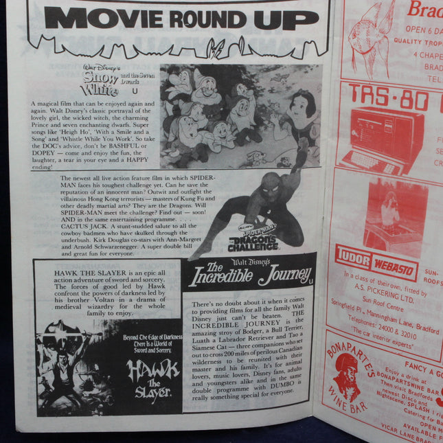 Vintage magazine or newspaper with movie round-up section and advertisements.