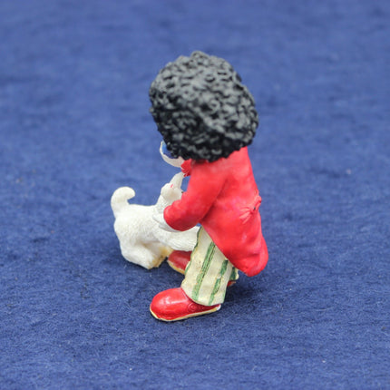Small figurine of a Golly sitting with a dog on a blue background