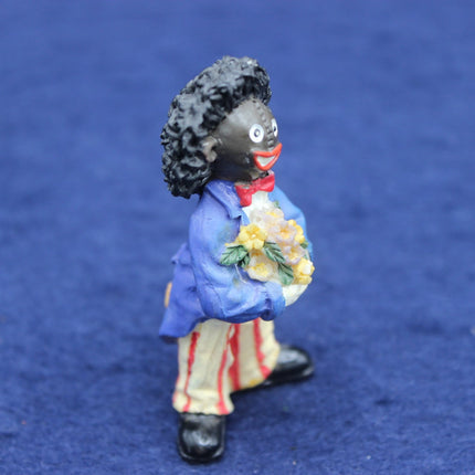 Figurine of a Golly in a blue coat holding flowers on a blue background