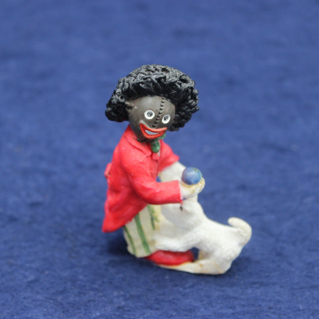 Figurine of a Golly in a red coat holding a dog on a blue background