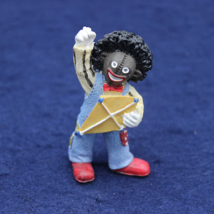 Toy figure of a Golly playing a drum on a blue background